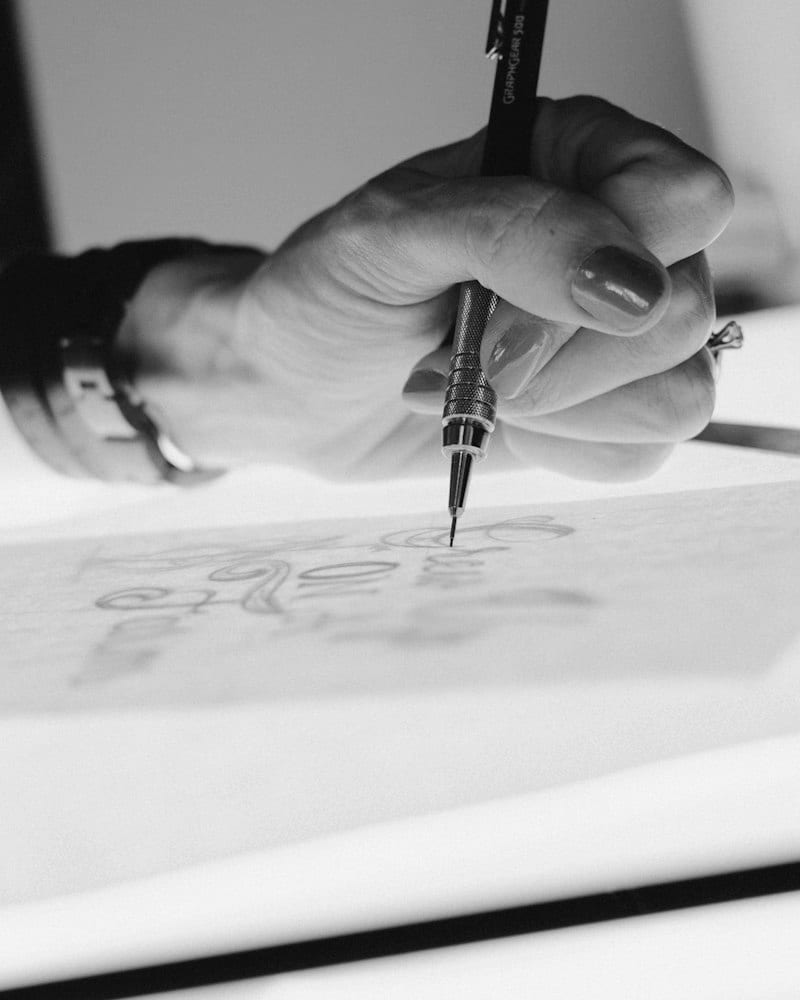 Close-up of a hand sketching with a mechanical pencil on tracing paper