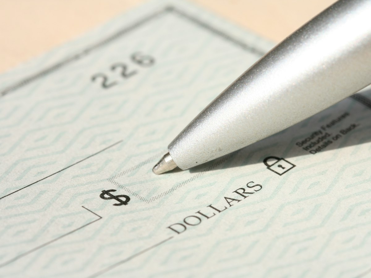 Close-up of a pen resting on a blank bank check with a security pattern