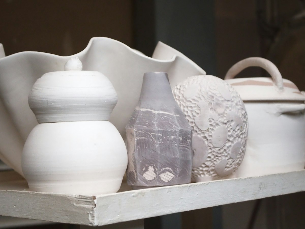 White glazed ceramic pots and vases neatly arranged on a shelf