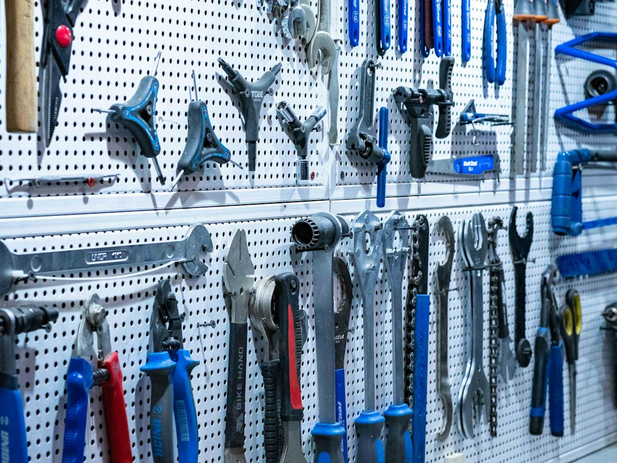 Wall of hand tools neatly organized on a white pegboard